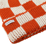 Side view of orange and ecru checkered knit merino beanie