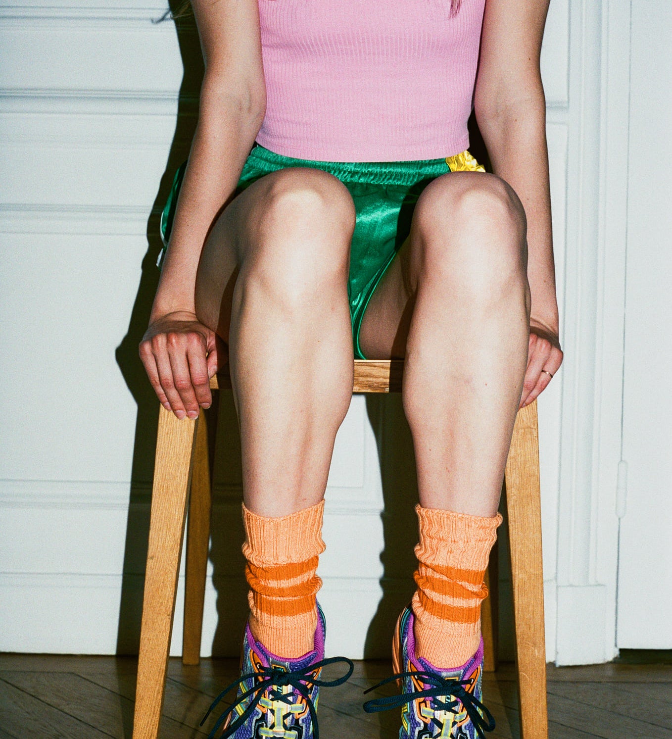 Person wearing colorful shoes and socks sitting on a chair indoors.