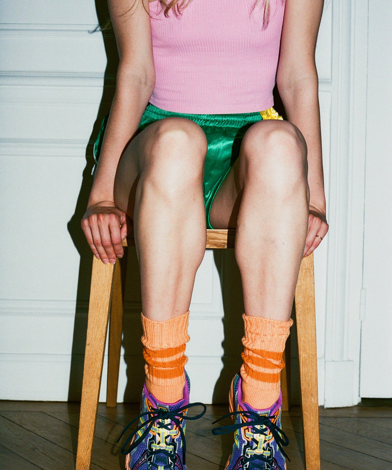 Person wearing colorful shoes and socks sitting on a chair indoors.