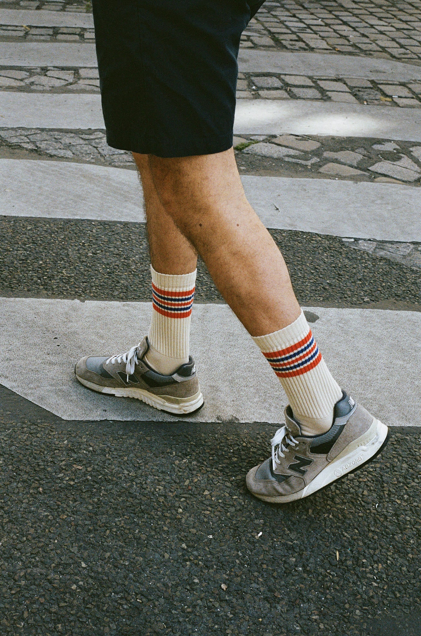 Person wearing striped socks and sneakers on a zebra crossing