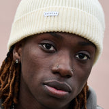 Person wearing a cream ribbed merino wool beanie by Escuyer